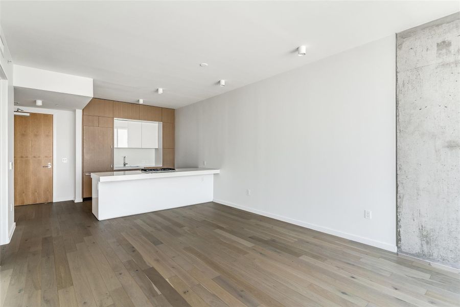 A modern kitchen and living area featuring sleek wood cabinetry and light-colored hardwood flooring. A modern kitchen and living area featuring sleek wood cabinetry and light-colored hardwood flooring.