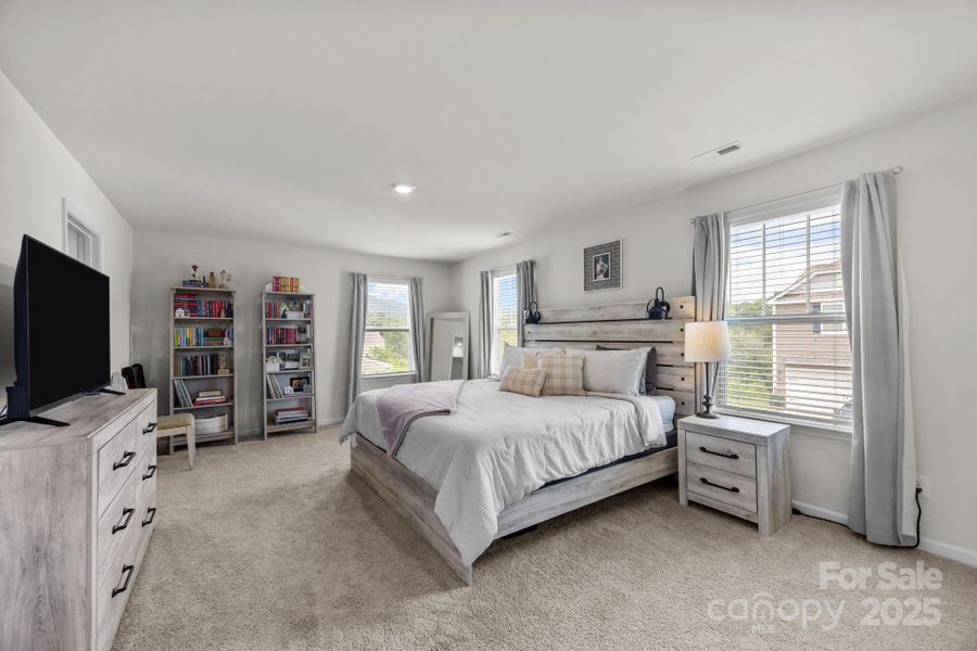 Large primary bedroom with lots of windows.