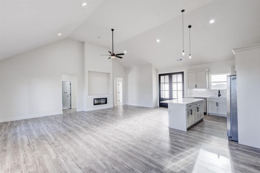 Kitchen with stainless steel appliances, ceiling fan, decorative light fixtures, high vaulted ceiling, and a kitchen island