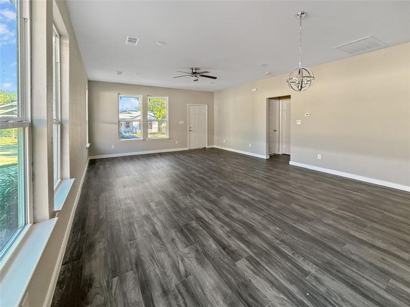 Unfurnished room with dark wood-style flooring, ceiling fan, and a chandelier