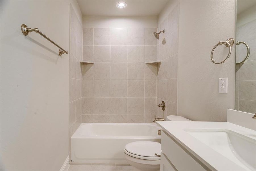 Full bathroom featuring tiled shower / bath combo, vanity, tile patterned flooring, and toilet
