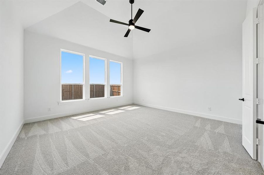 Empty room with light colored carpet, high vaulted ceiling, and a ceiling fan