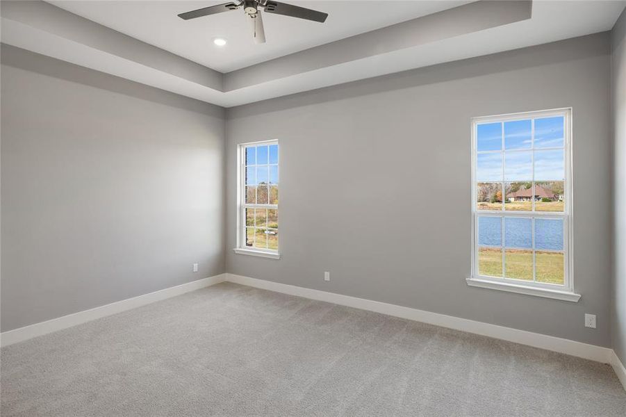 Unfurnished room with light carpet, a tray ceiling, recessed lighting, ceiling fan, and a water view Unfurnished room with light carpet, a tray ceiling, recessed lighting, ceiling fan, and a water view