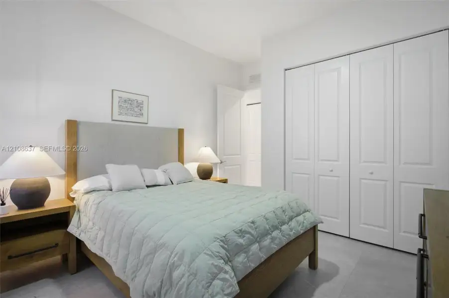 Room featuring neutral wall tones, large format tile flooring, and a floor-to-ceiling closet with white paneled bi-fold doors
