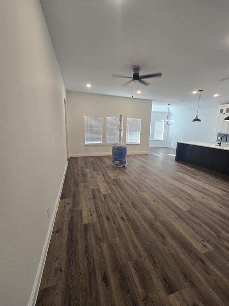 Unfurnished living room featuring dark wood-style flooring, a chandelier, a ceiling fan, and recessed lighting
