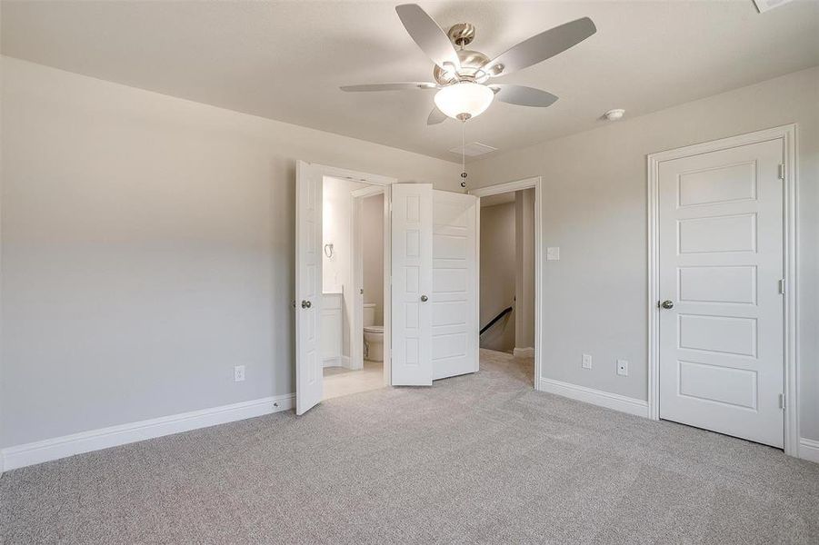 Unfurnished bedroom featuring light colored carpet, ensuite bath, and ceiling fan Unfurnished bedroom featuring light colored carpet, ensuite bath, and ceiling fan