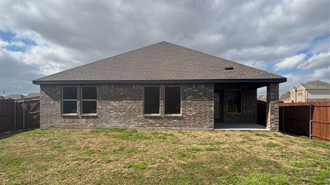 Rear view of house with a fenced backyard, a patio, and brick siding