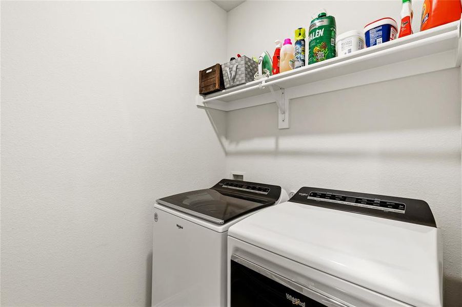Dedicated laundry area featuring a white wall shelf, white textured walls, and a level shelf installation