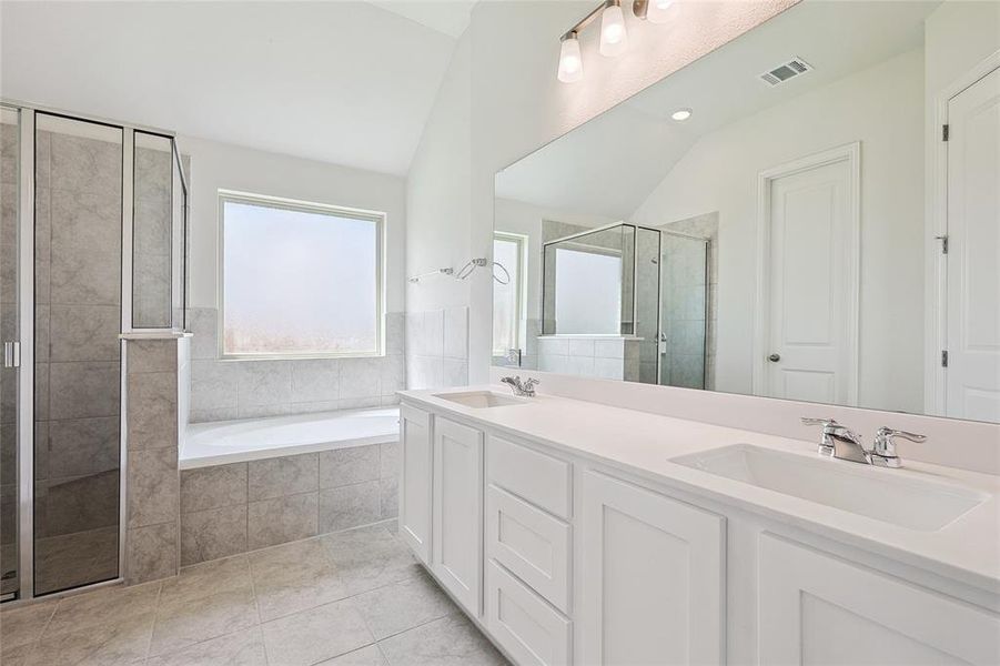 Bathroom featuring independent shower and bath, lofted ceiling, vanity, and tile patterned flooring