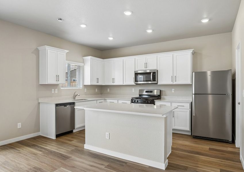 The kitchen has stainless steel appliances and plank flooring.