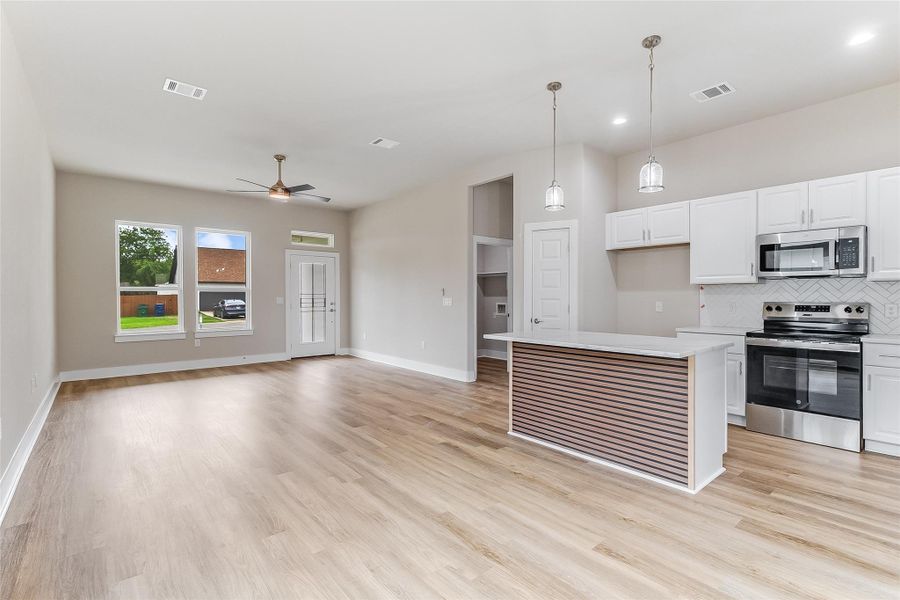 Kitchen with stainless steel appliances, ceiling fan, tasteful backsplash, light countertops, and white cabinets