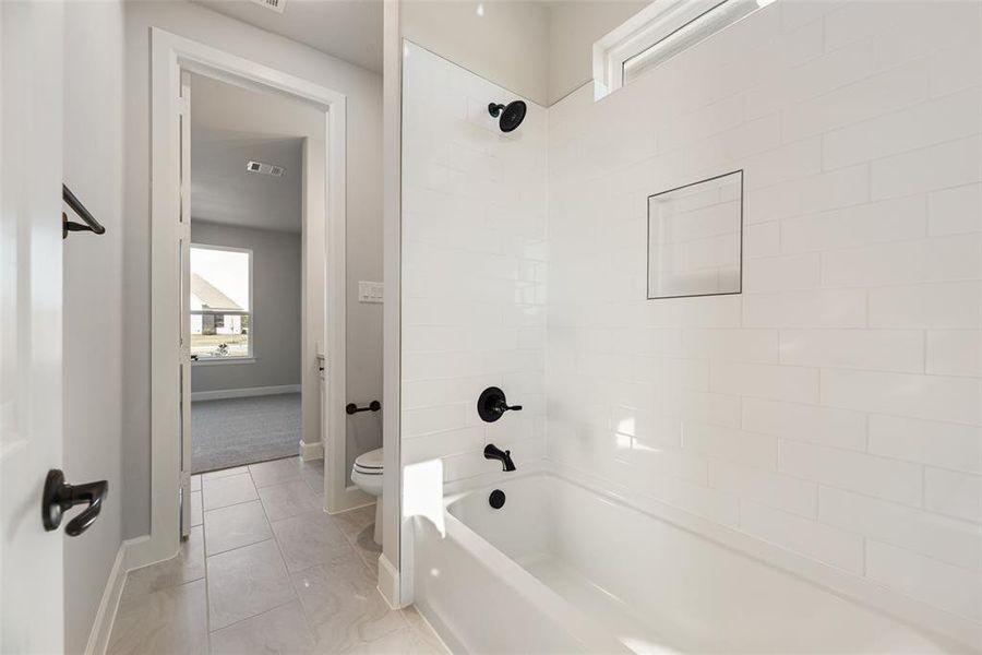 Full bathroom featuring healthy amount of natural light and shower / bath combination Full bathroom featuring healthy amount of natural light and shower / bath combination