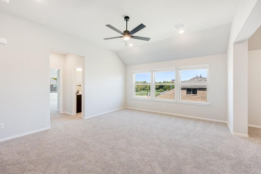 Empty bedroom with vaulted ceiling, ceiling fan, carpet flooring, and two windows with natural light Empty bedroom with vaulted ceiling, ceiling fan, carpet flooring, and two windows with natural light