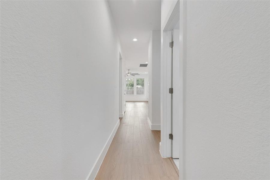 Hall with light wood finished floors, a textured wall, and recessed lighting Hall with light wood finished floors, a textured wall, and recessed lighting