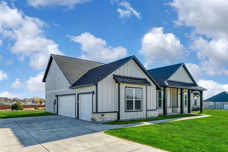 View of front of house featuring a porch, a garage, and a front lawn