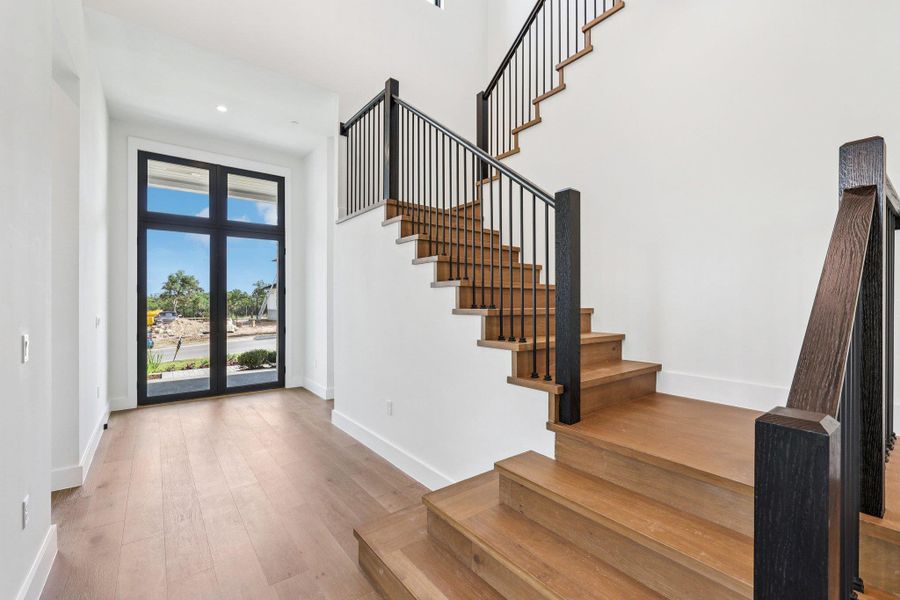 Entryway with a high ceiling, light wood-style floors, recessed lighting, and stairway