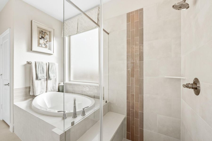 Ensuite bathroom with round soaking tub, glass-enclosed walk-in shower, and neutral tile walls Ensuite bathroom with round soaking tub, glass-enclosed walk-in shower, and neutral tile walls