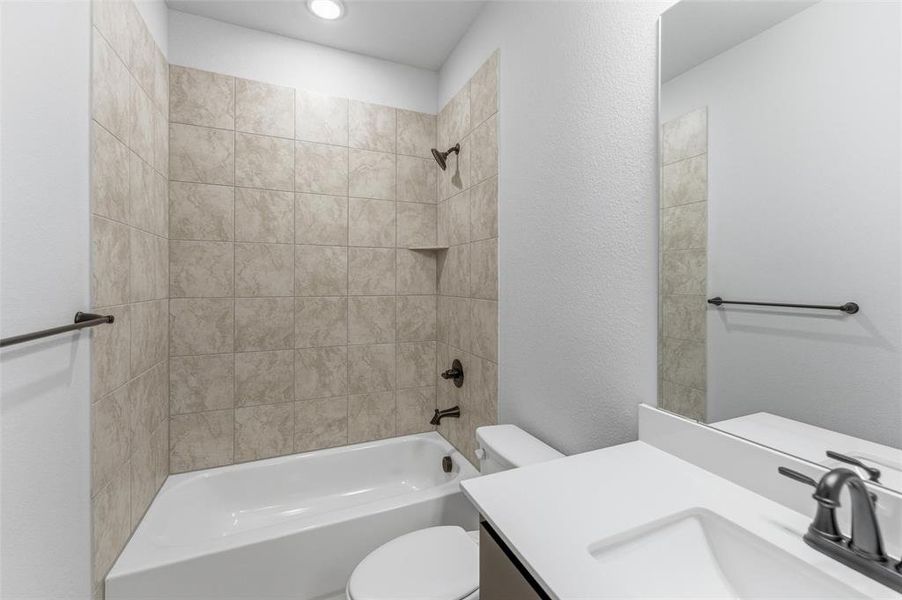 Bathroom with vanity, bathtub / shower combination, and a textured wall