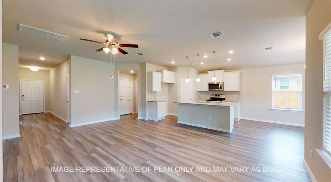 Kitchen with open floor plan, a kitchen island with sink, white cabinetry, pendant lighting, and light wood-style floors Kitchen with open floor plan, a kitchen island with sink, white cabinetry, pendant lighting, and light wood-style floors