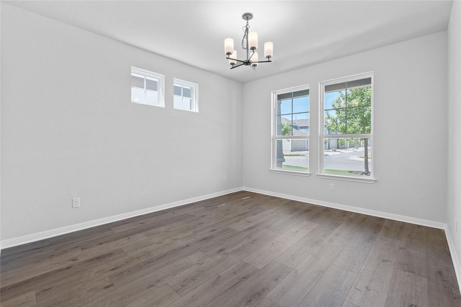 Empty room with a chandelier and dark wood finished floors