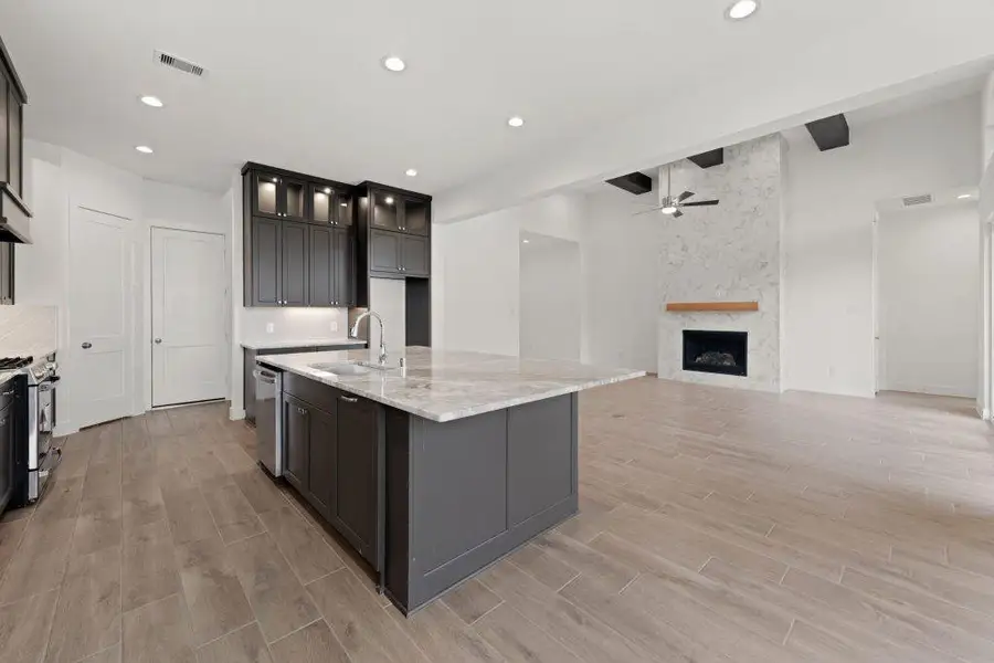 A grand central island anchors the open-concept layout, offering both functionality and a visual connection to the inviting living area beyond.