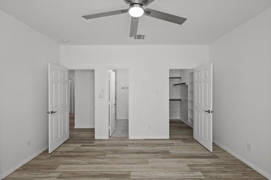 Unfurnished bedroom with baseboards, visible vents, light wood-style flooring, a closet, and a walk in closet