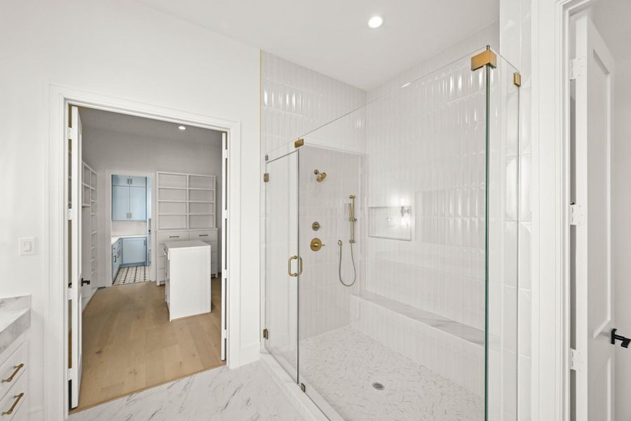 The walk-in shower enjoys a bench, hand sprayer, and storage alcove!