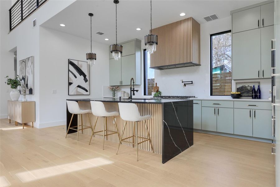 Kitchen featuring a kitchen island with sink, a kitchen breakfast bar, light wood-style floors, healthy amount of natural light, and two tone cabinetry