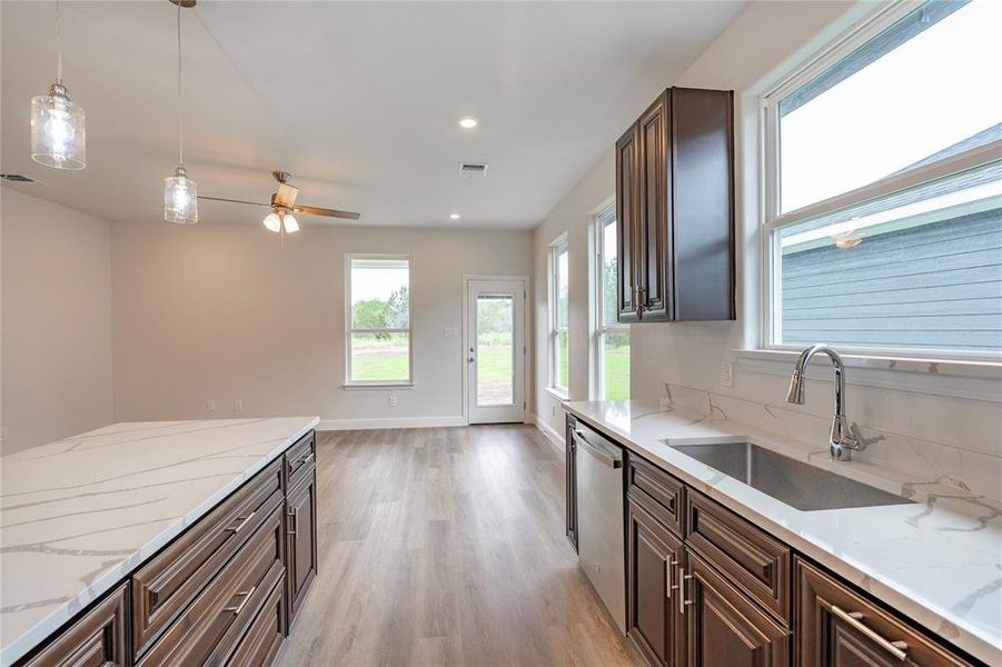 Kitchen featuring decorative light fixtures, light hardwood / wood-style flooring, stainless steel dishwasher, sink, and ceiling fan