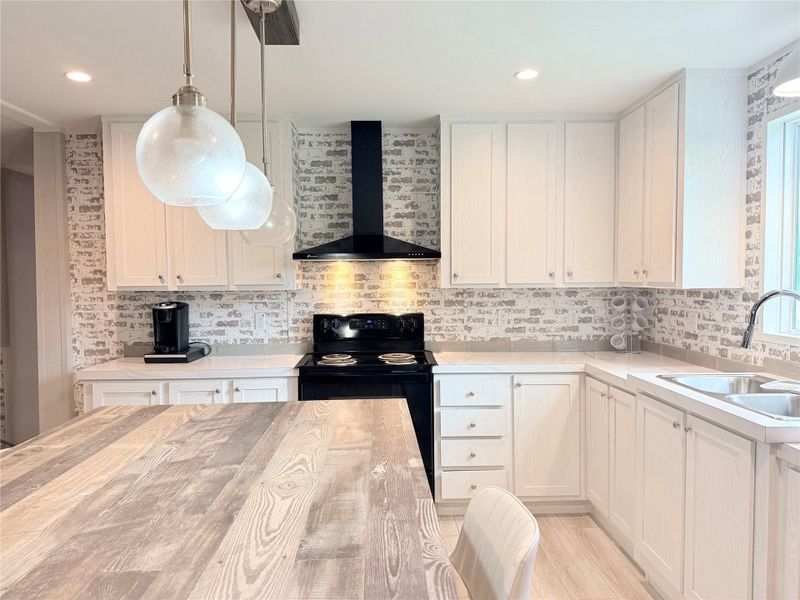 White cabinetry and an expansive island define this beautifully appointed, naturally illuminated kitchen.
