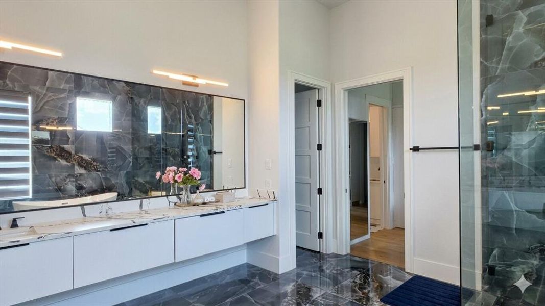 Bathroom featuring a dual vanity with white cabinetry, white countertops, and contemporary black fixtures