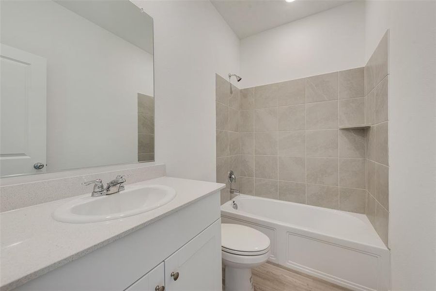 Full bathroom featuring wood-type flooring, vanity, toilet, and tiled shower / bath