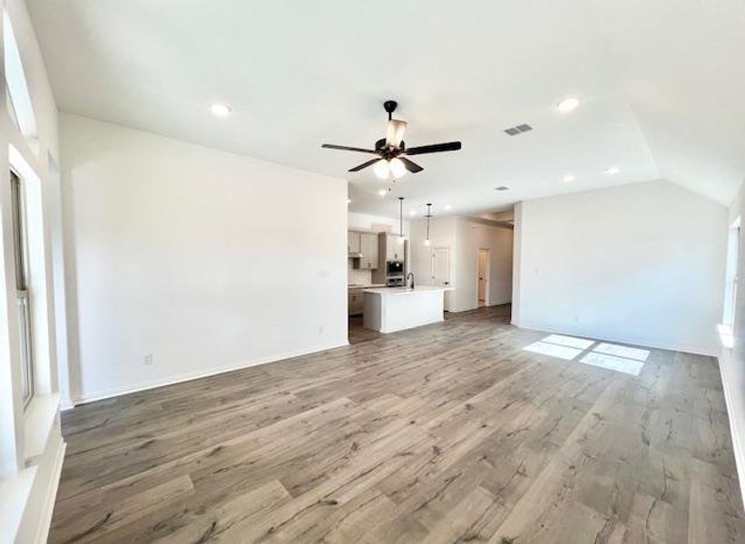 Unfurnished living room featuring recessed lighting, a ceiling fan, light wood-style floors, visible vents, and lofted ceiling Unfurnished living room featuring recessed lighting, a ceiling fan, light wood-style floors, visible vents, and lofted ceiling