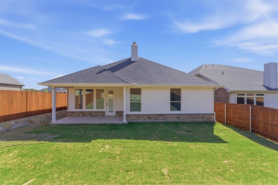 Rear view of property featuring brick siding, a patio area, a fenced backyard, roof with shingles, and a chimney