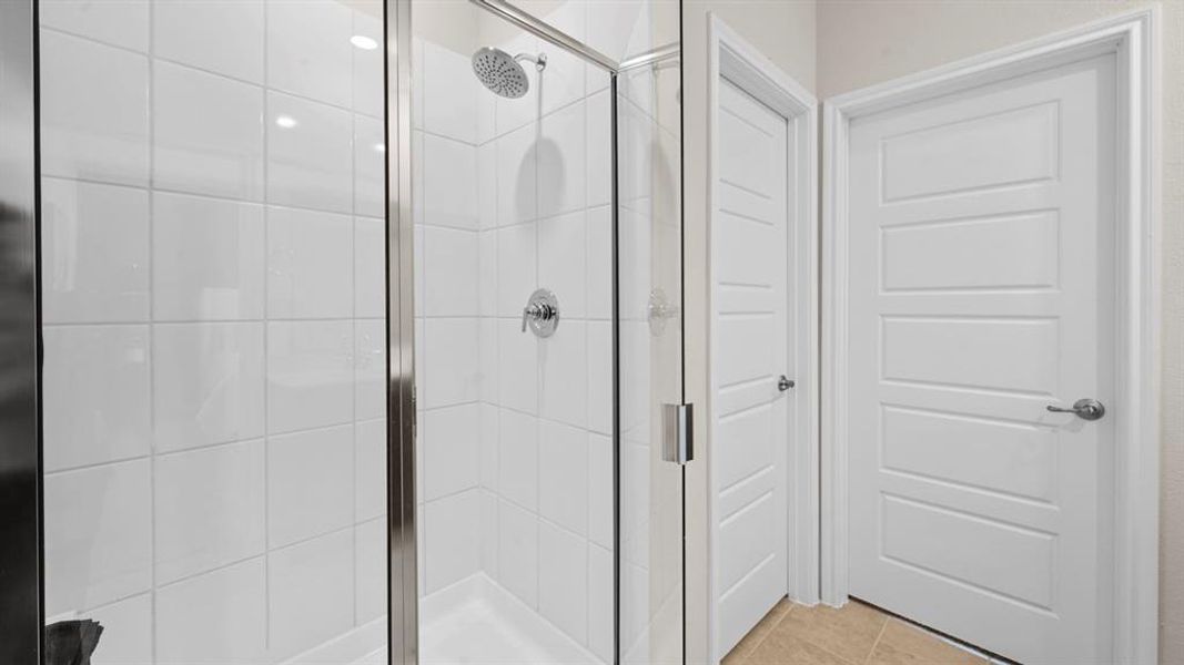 Bathroom featuring a shower stall and light tile patterned flooring