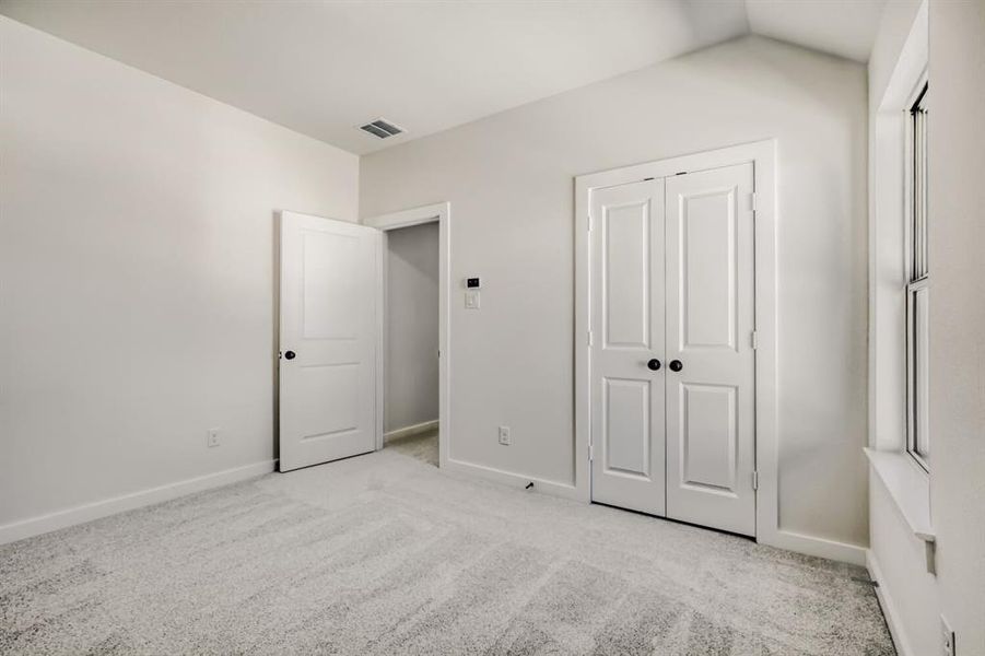 Unfurnished bedroom with light colored carpet and a closet