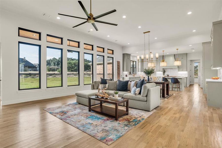 Living area with recessed lighting, light wood finished floors, a ceiling fan, and a chandelier
