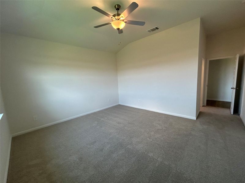 Carpeted empty room featuring lofted ceiling and ceiling fan Carpeted empty room featuring lofted ceiling and ceiling fan