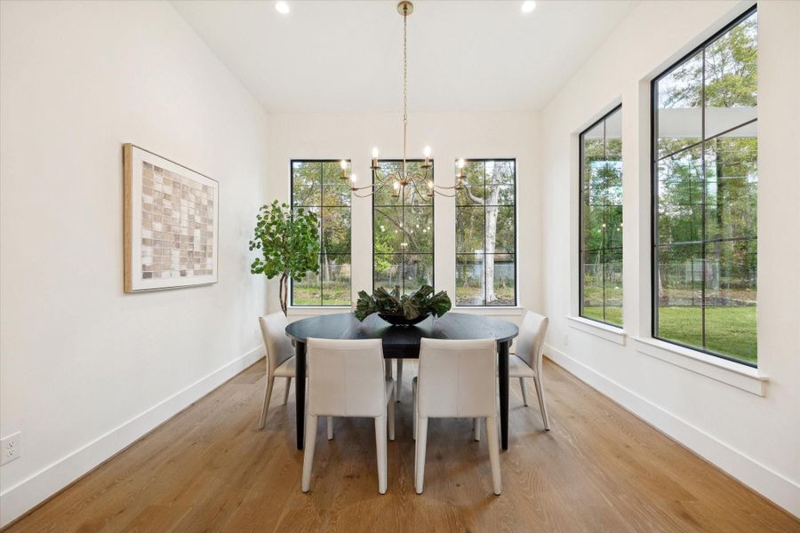 Bright dining area with large picture windows, custom designer lighting, and white oak wood flooring.