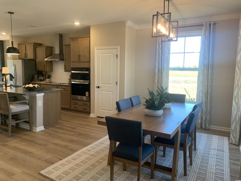 Dining area featuring light wood finished floors, a chandelier, recessed lighting, and ornamental molding