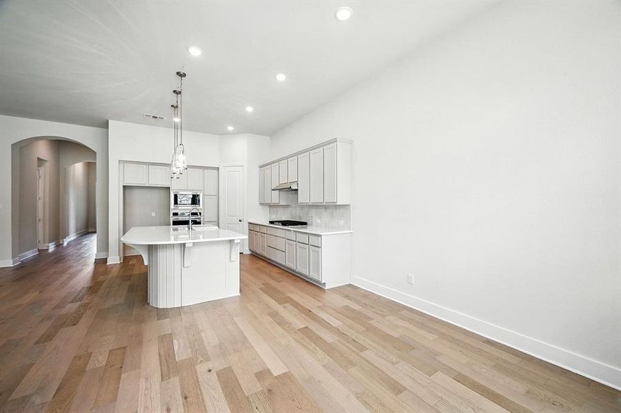 Kitchen with arched walkways, a kitchen bar, recessed lighting, tasteful backsplash, and an island with sink Kitchen with arched walkways, a kitchen bar, recessed lighting, tasteful backsplash, and an island with sink