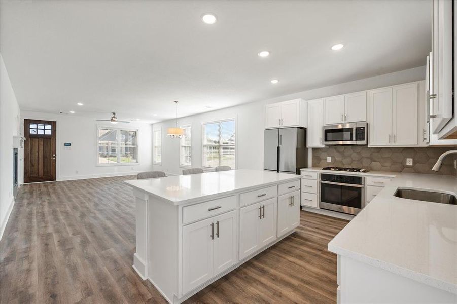 Kitchen featuring recessed lighting, tasteful backsplash, a kitchen island, dark wood finished floors, and appliances with stainless steel finishes