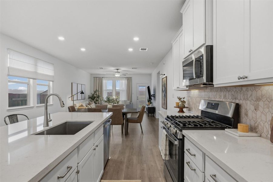 Modern kitchen featuring white shaker cabinetry, stainless steel appliances, a gas range, and a geometric tile backsplash