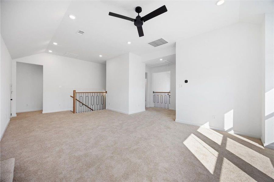 This spacious, well-lit room features carpeted flooring, white walls, recessed lighting, and a modern ceiling fan. It includes multiple entry points and a railing, ideal for a versatile living space or loft area. This spacious, well-lit room features carpeted flooring, white walls, recessed lighting, and a modern ceiling fan. It includes multiple entry points and a railing, ideal for a versatile living space or loft area.