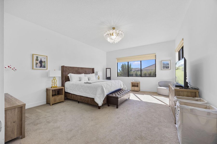 Bedroom featuring light colored carpet and a chandelier