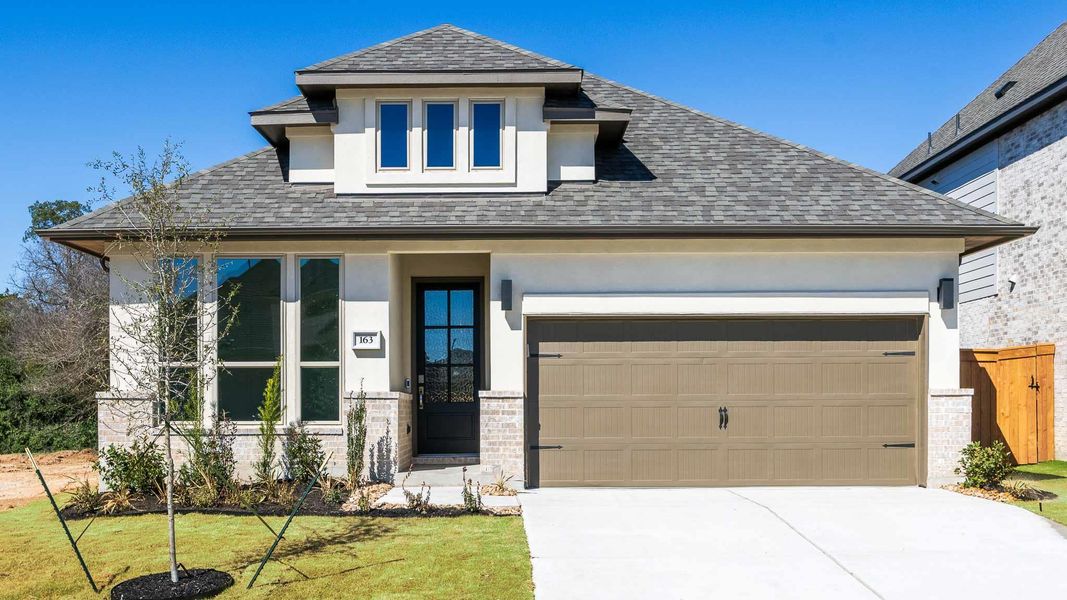 Prairie-style house featuring stucco siding, driveway, an attached garage, and roof with shingles