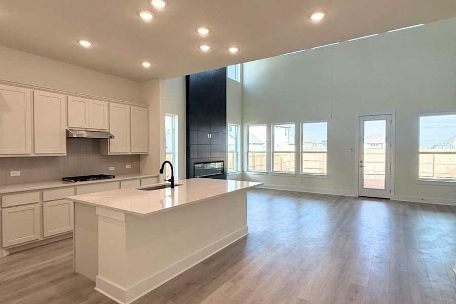 A stylish kitchen island overlooks a spacious living area with soaring ceilings and a sleek fireplace. A stylish kitchen island overlooks a spacious living area with soaring ceilings and a sleek fireplace.