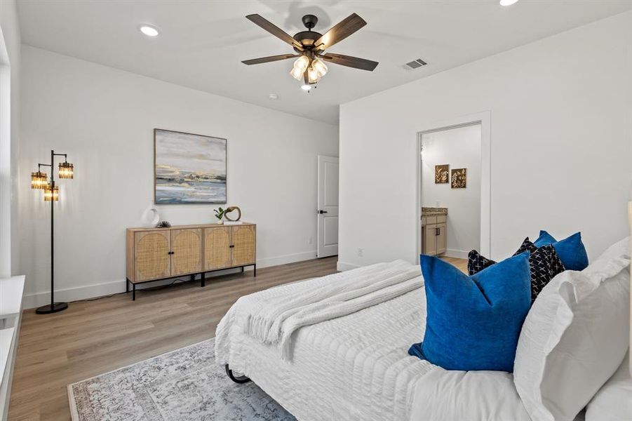 Bedroom featuring visible vents, baseboards, recessed lighting, light wood-style floors, and ensuite bath