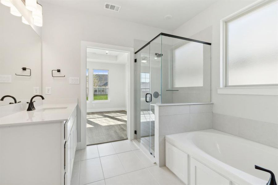 Bathroom featuring tile patterned flooring, vanity, and shower with separate bathtub