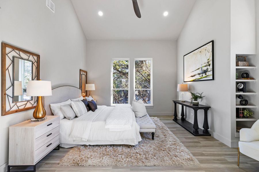 Bedroom with multiple windows, wood finished floors, visible vents, and high vaulted ceiling